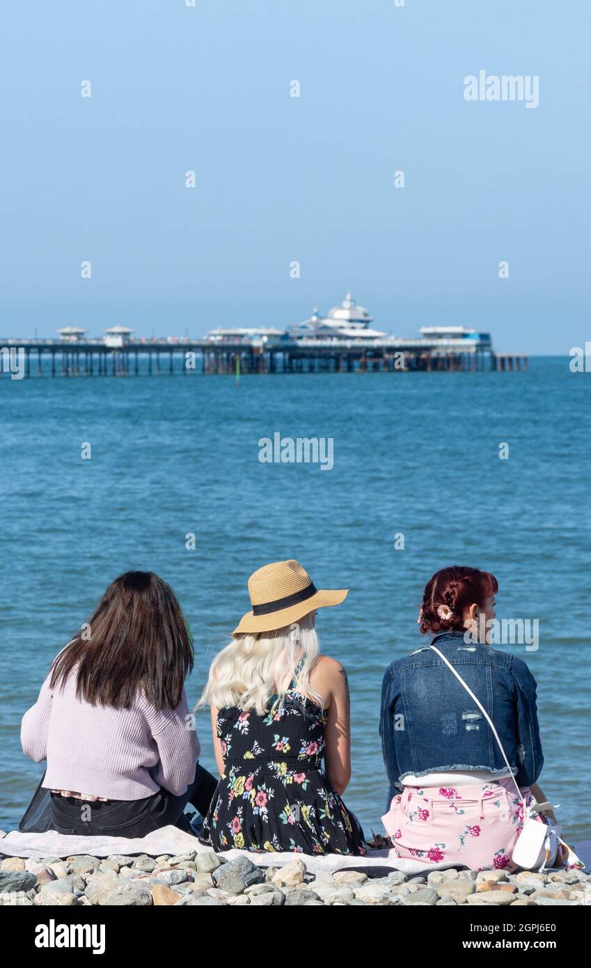 Giovani donne che siedono sulla spiaggia, Llandudno, Conwy County Borough, Galles, Regno Unito Foto Stock