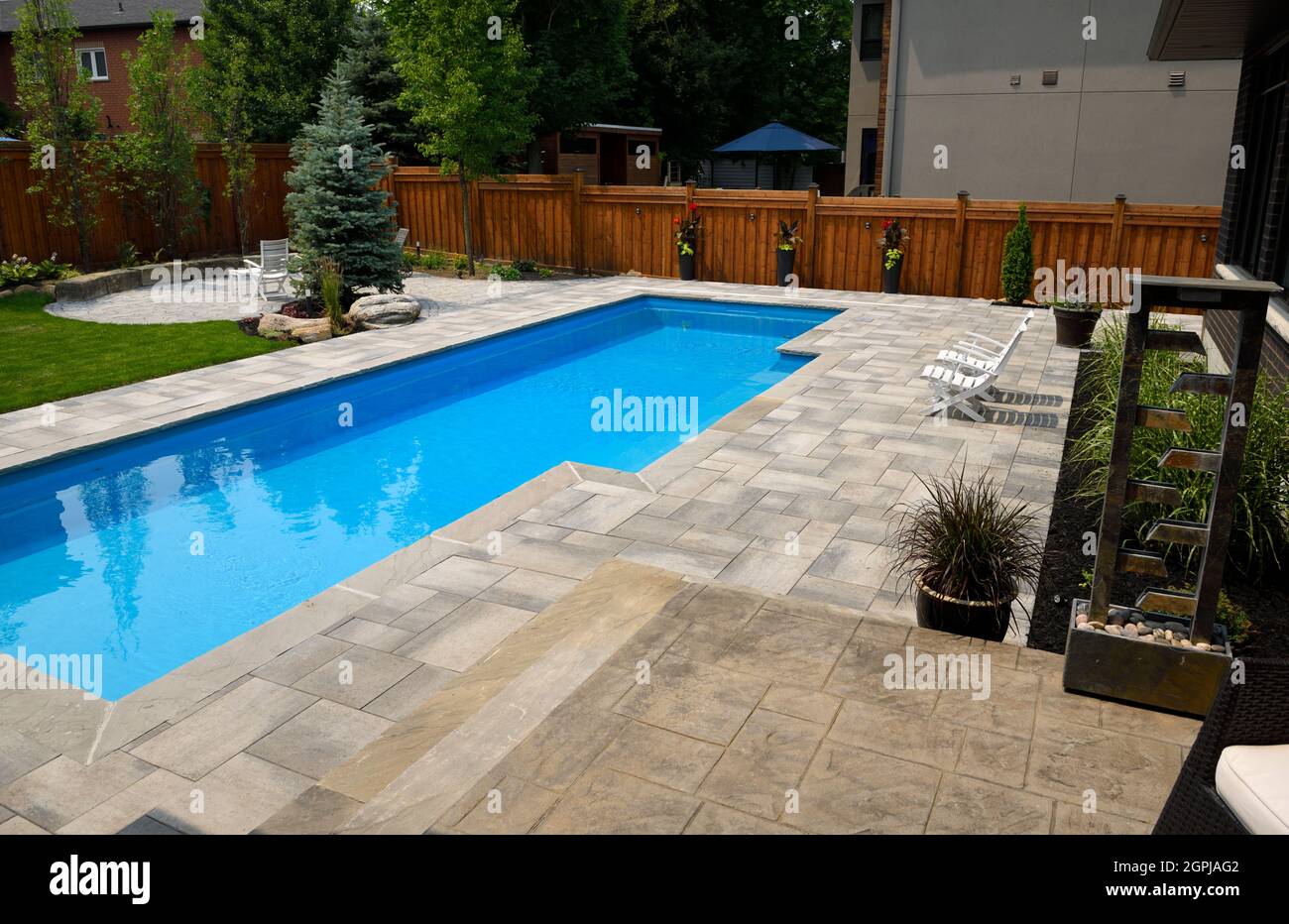 Completato il paesaggio intorno alla nuova piscina lap nel cortile posteriore con i giardini del patio del asfaltatore ed il prato Barrie Ontario Canada Foto Stock