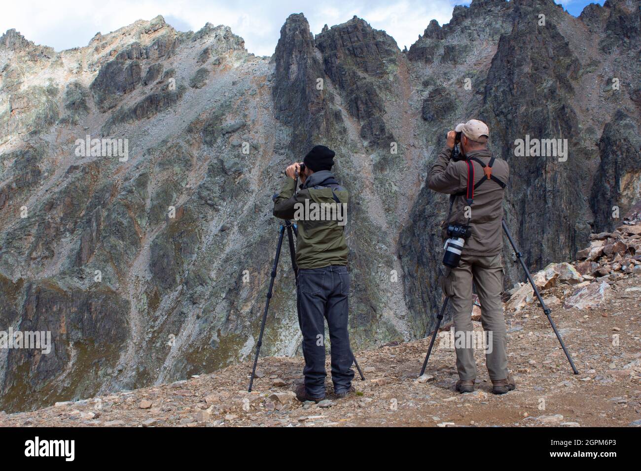 Fotografi professionisti che scattano foto in alta montagna. Due uomini con attrezzatura fotografica stanno su una roccia. Foto Stock