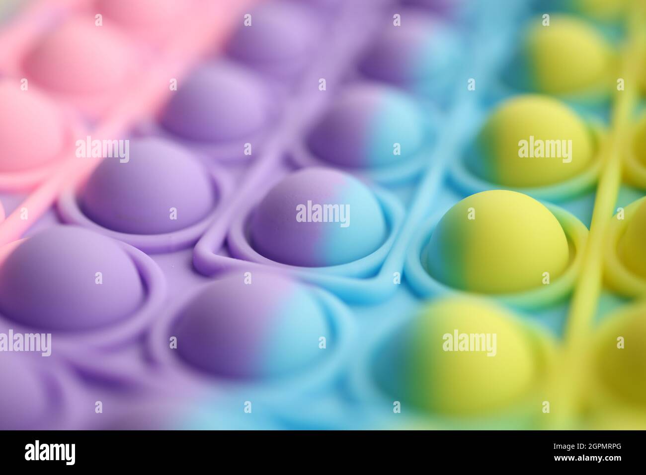 La pellicola multicolore a bolle d'aria lo schiocca in colori brillanti sul tavolo Foto Stock