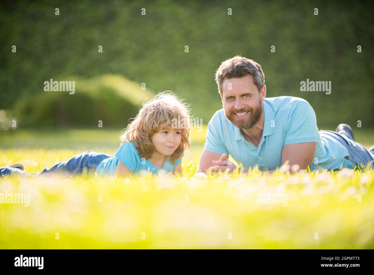 famiglia felice di papà e bambino rilassarsi nel parco estivo erba verde, giorno dei padri Foto Stock