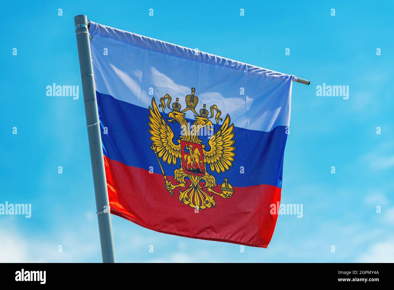 Bandiera russa con stemma, aquila a due teste senza scudo contro il cielo blu Foto Stock