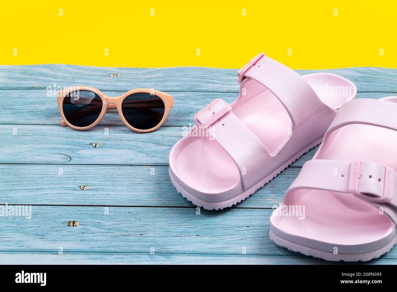 Le sneaker e gli occhiali estivi sono su uno sfondo isolato misto blu e giallo. Foto Stock