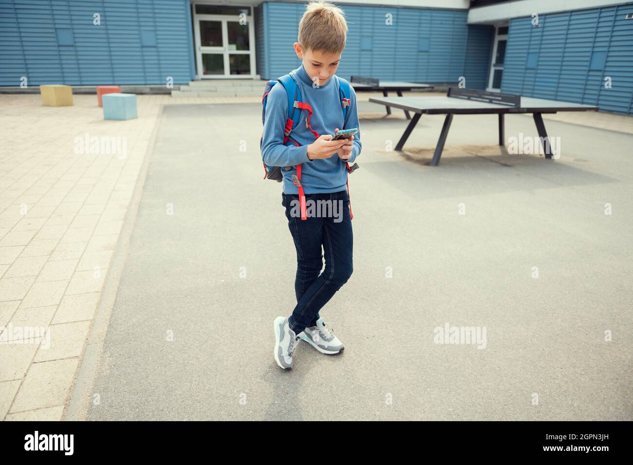 Ritratto di bel ragazzo della scuola teen che naviga in internet usando il telefono cellulare Foto Stock