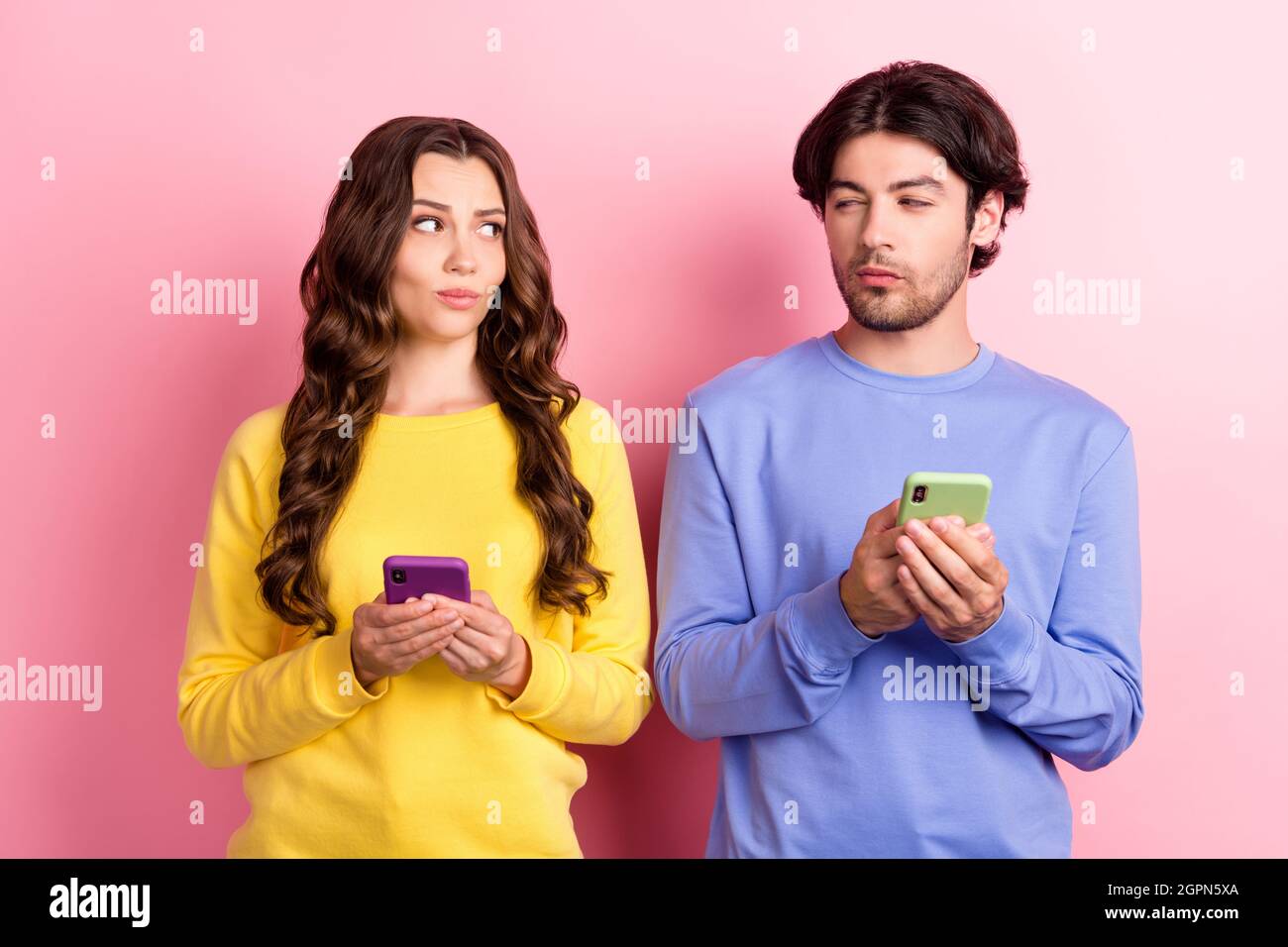 Foto di giovane coppia fidanzata fidanzata tenere smartphone sospetto incerto isolato su sfondo rosa Foto Stock
