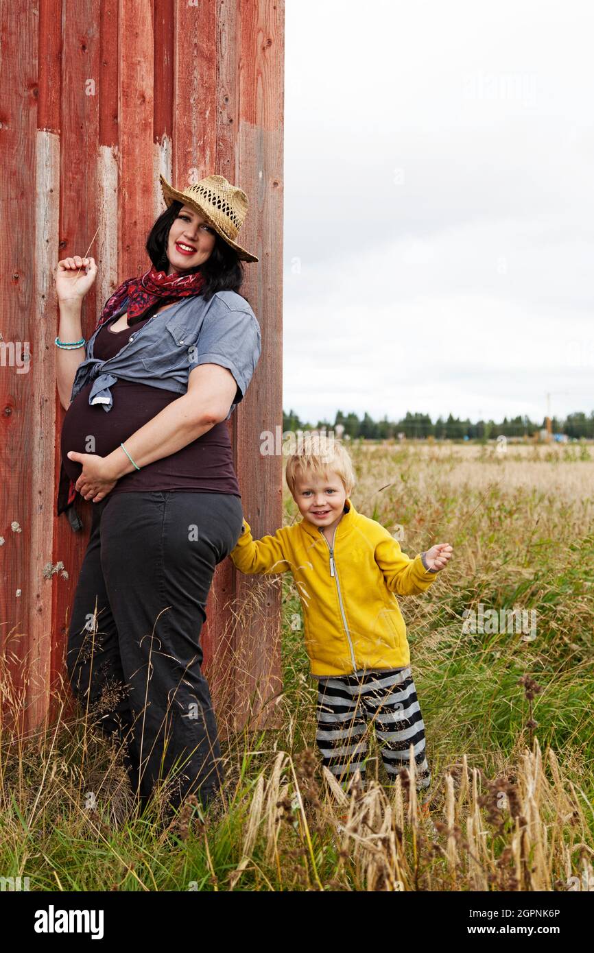 Umea, Norrland Svezia - 22 agosto 2021: Madre incinta e figlio che gioca nel prato Foto Stock