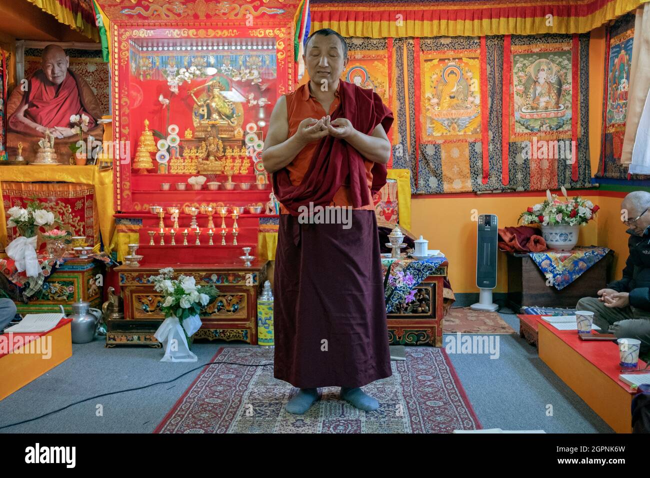 Un monaco di una congregazione di Sherpa insegna la sua congregazione in gesti nepalesi e tibetani a portata di mano durante la preghiera. A Elmhurst, Queens, New York City. Foto Stock