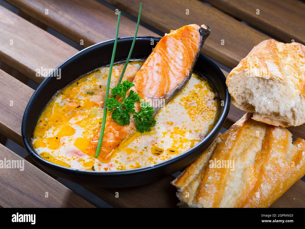 Deliziosa zuppa di salmone cremosa in ciotola nera servita con baguette Foto Stock