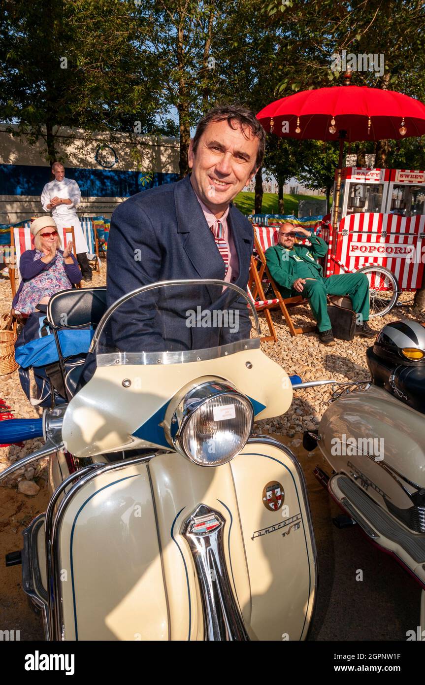 La stella di Quadrophenia Phil Daniels ha aperto il Goodwood Revival guidando un gruppo di 'mods' intorno al circuito. Seduto su uno scooter Lambretta. Foto Stock