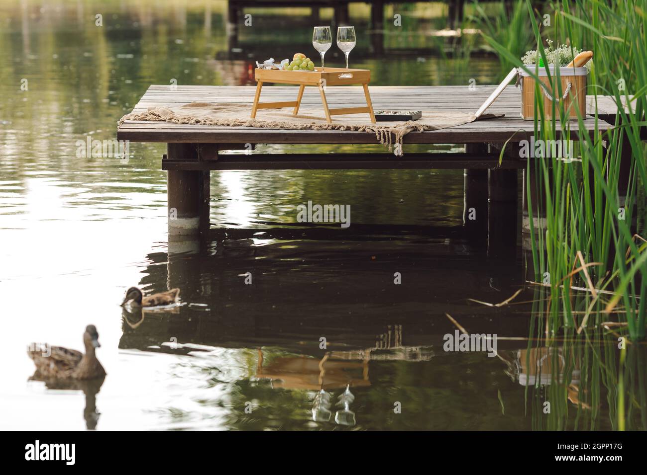 Ottimo tempo per un picnic sul molo di legno con tavolo con vino e frutta. Data romantica. Attività ricreative e viaggi. Bella estate sevenes.Tourism ed e Foto Stock