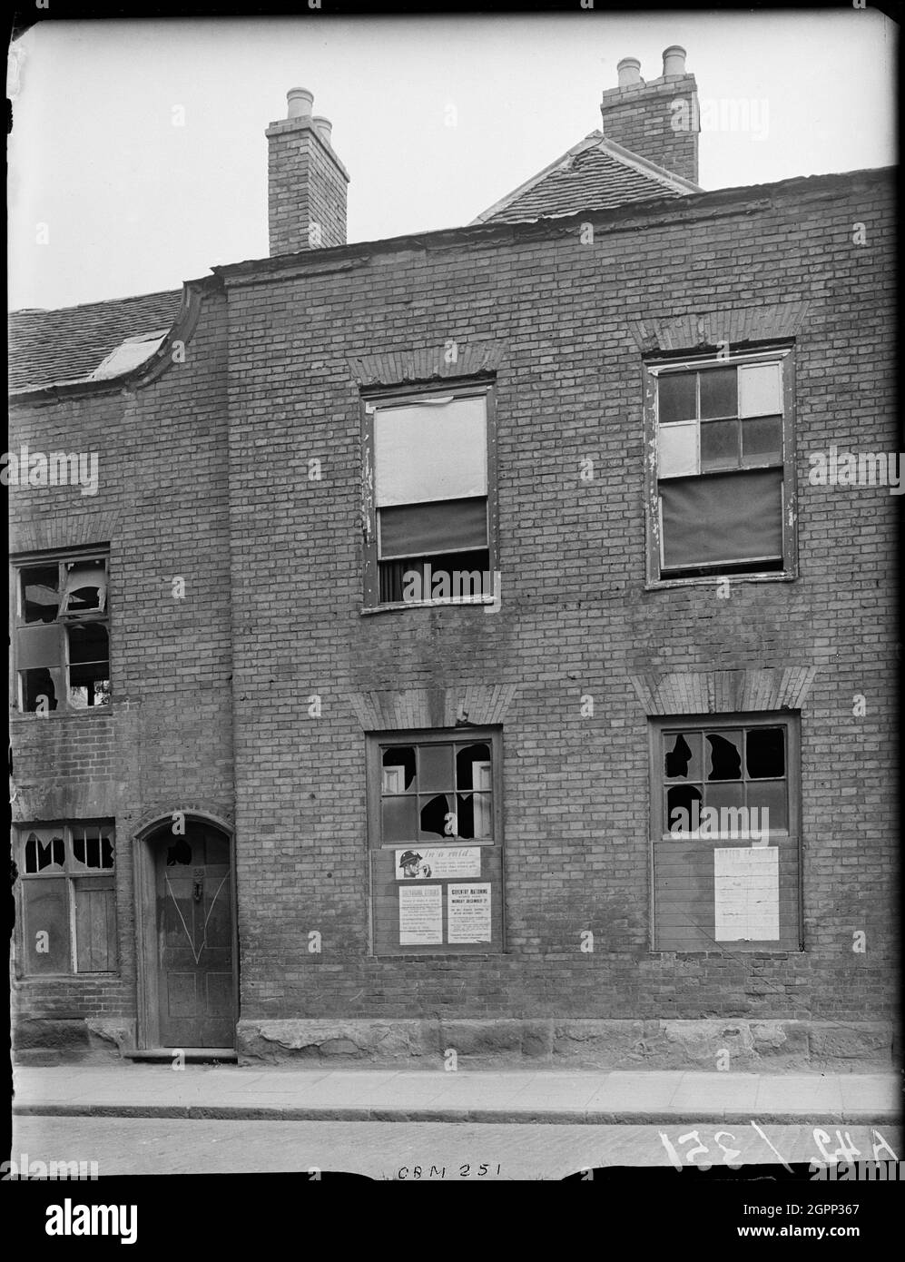 Little Park Street, Coventry, 1941. L'esterno di 92 Little Park Street mostra danni bomba alla facciata e avvisi relativi al razionamento e incursioni d'aria apparsi sulle tavole che coprono le finestre rotte. Il centro di Coventry è stato devastato dalle incursioni aeree nel novembre 1940. I bombardamenti lasciarono la cattedrale in rovina e distrussero gran parte del tessuto storico della città. Gran parte di Little Park Street è stata demolita. La Corte dei Magistrati occupa ora il sito di questa casa. Foto Stock