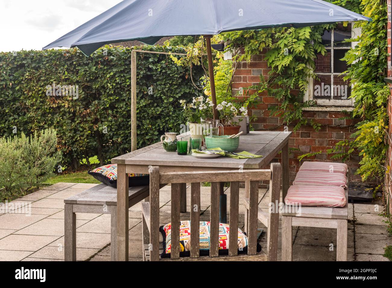 Ombrellone sulla terrazza con tavolo e panche, casale Sussex, Regno Unito Foto Stock