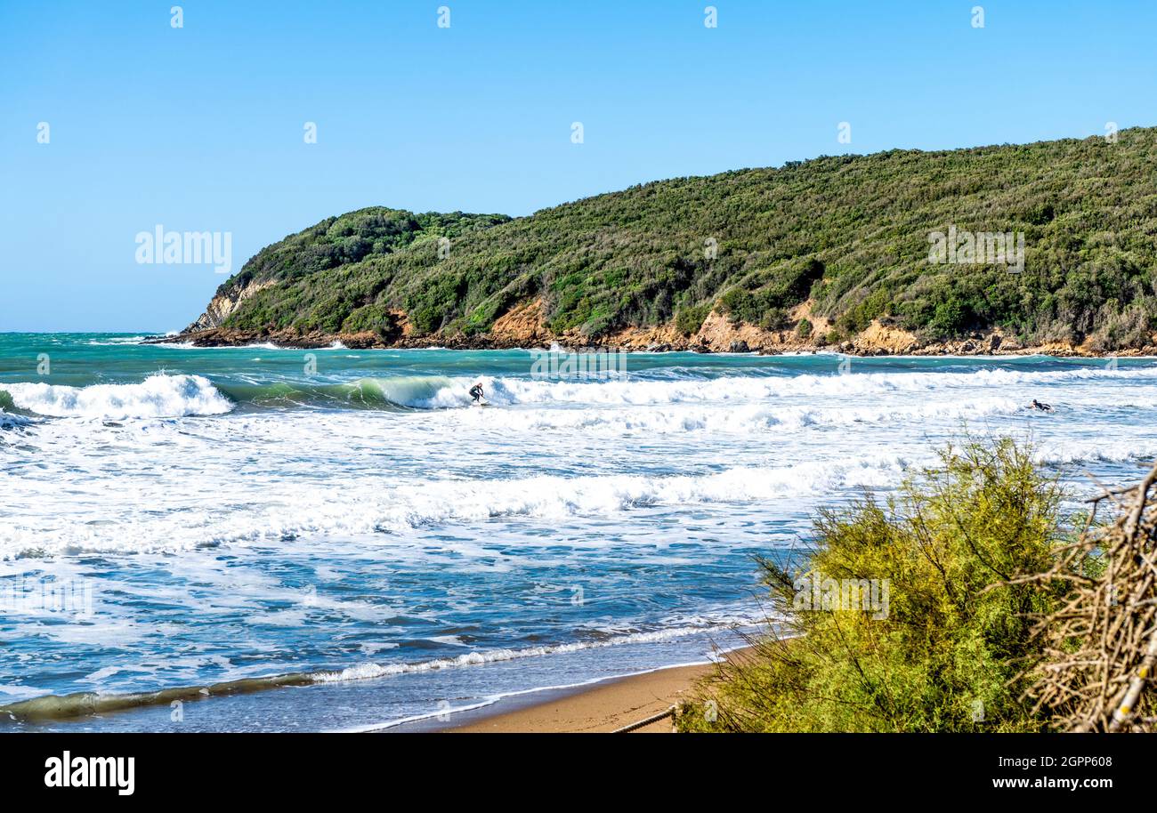 Onde marine nel golfo di Baratti, Piombino, provincia di Livorno, Italia. Un surfer in lontananza. Foto Stock