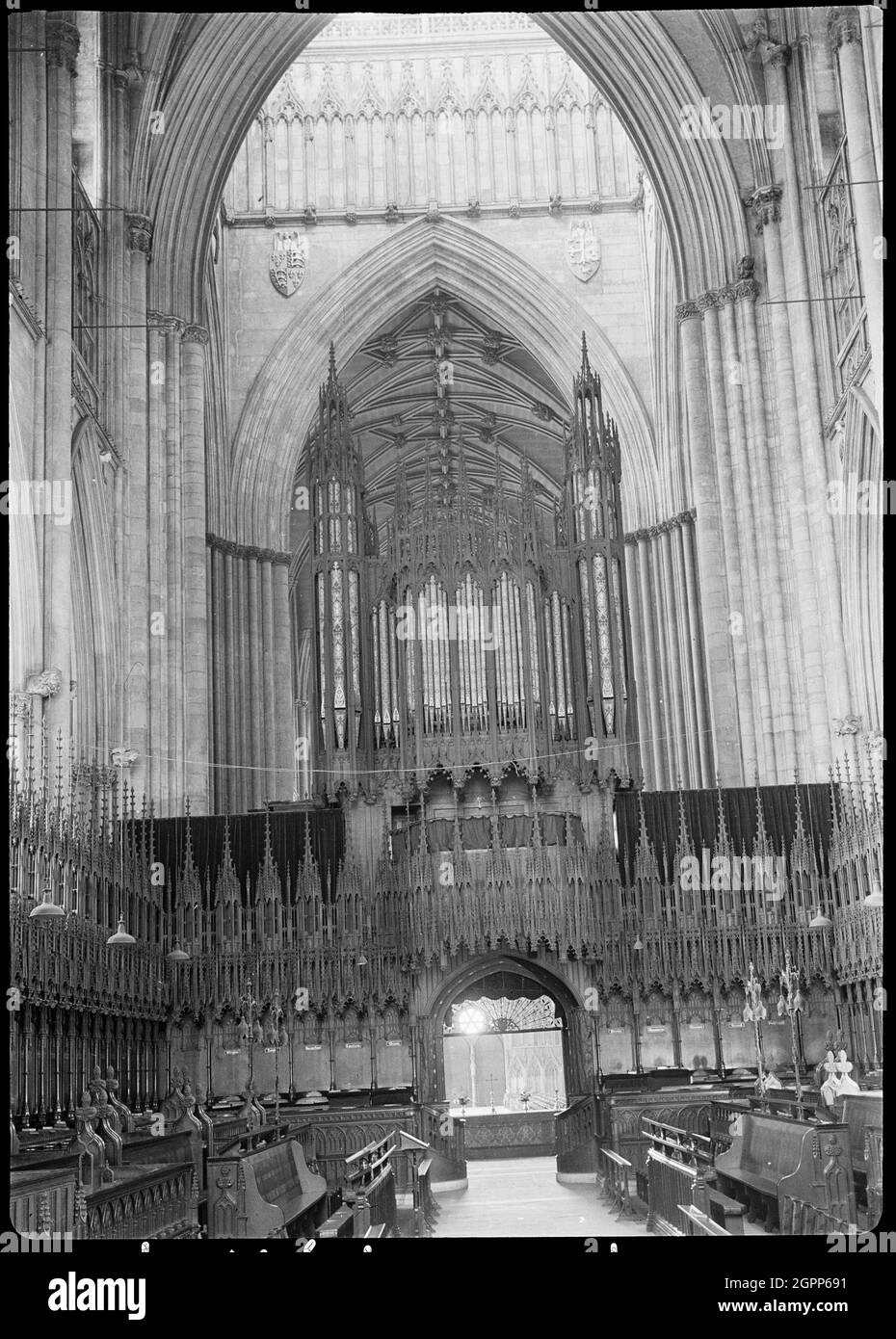 York Minster, Minster Yard, York, 1942. Una vista interna della York Minster, conosciuta anche come St Peter's Cathedral Church, che guarda ad ovest dal coro e mostra lo schermo del coro e attraversa lo sfondo. Lo schermo del coro si trova sotto l'arco orientale, e presenta nicchie con figure scolpite sul lato occidentale. Il lato orientale ha una struttura in legno gotico con una porta centrale. Lo schermo, il pulpito e il trono dell'arcivescovo sono tutti gotici e di Sir Robert Smirke dopo un incendio nel 1829. Sono in armonia con gli accessori originali del XV secolo. Foto Stock