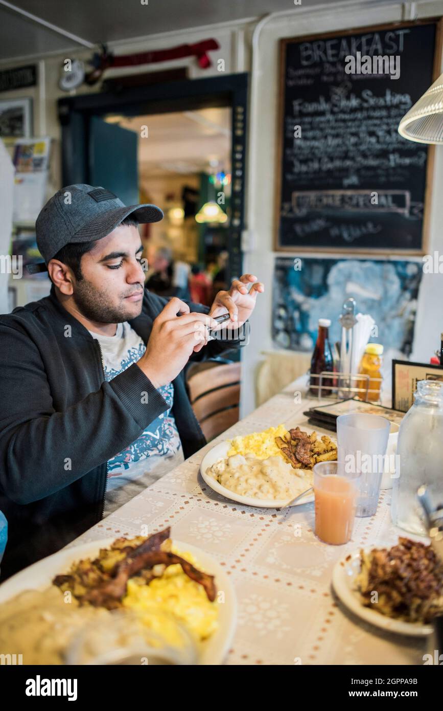 USA, uomo che fotografa la colazione in ristorante con smartphone Foto Stock