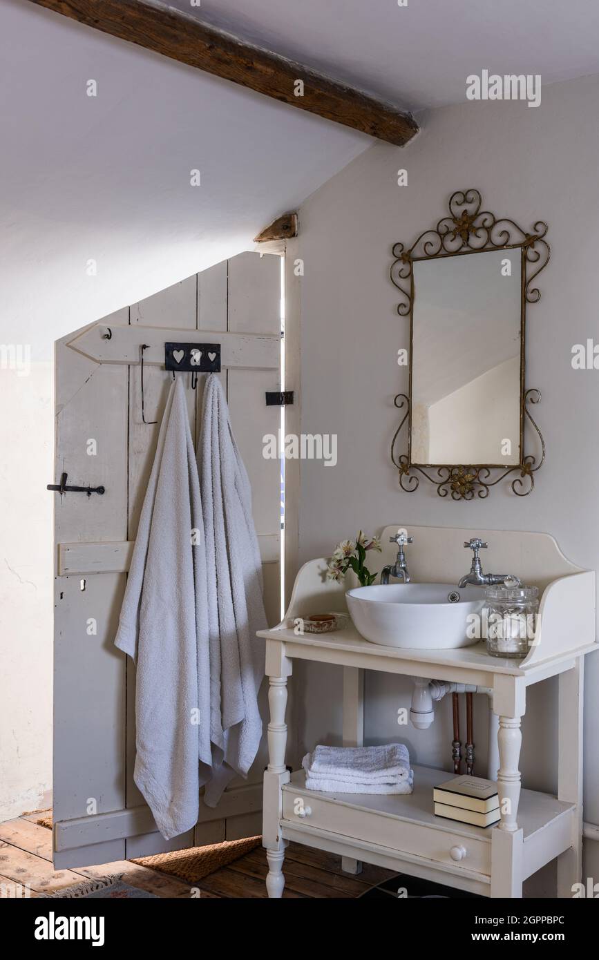 Specchio decorativo vintage sopra il banco di lavaggio in soffitta bagno del cottage Suffolk. Foto Stock