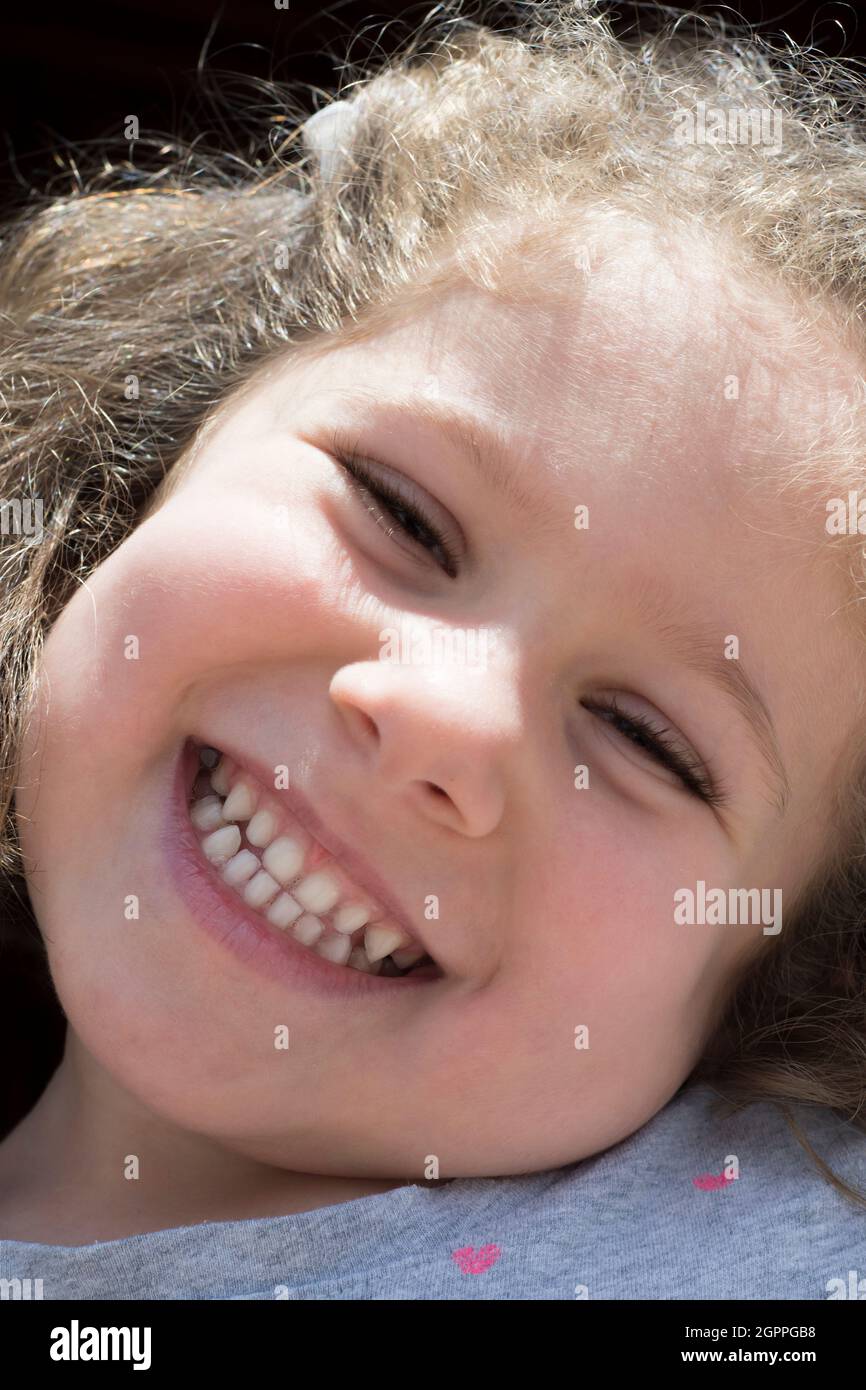 La bambina sta guardando la macchina fotografica con un grande sorriso. Fuoco selettivo volto della ragazza. Foto Stock