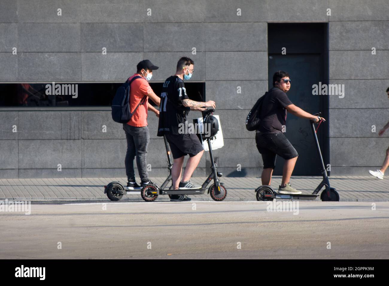 Gruppo di uomini con il loro scooter elettrico stanno aspettando in una strada. Foto Stock