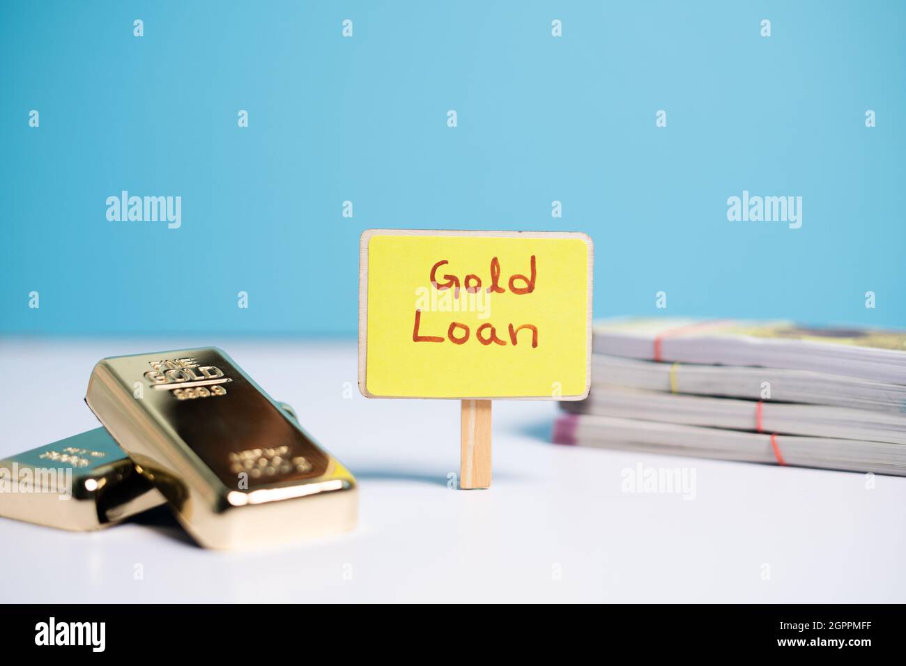 Fuoco sulle lettere di prestito d'oro, concetto di prestito d'oro che mostra wiyh Gold prestito segno bordo con barre d'oro e banconote di valuta sul tavolo. Foto Stock