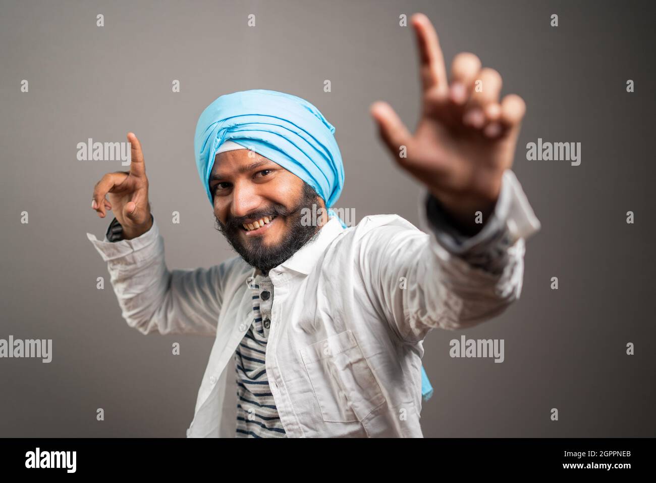 Giovane uomo sikh Balle balle Gurmukhi stile indiano danza culturale su sfondo studio - concetto di felicità e relax Foto Stock