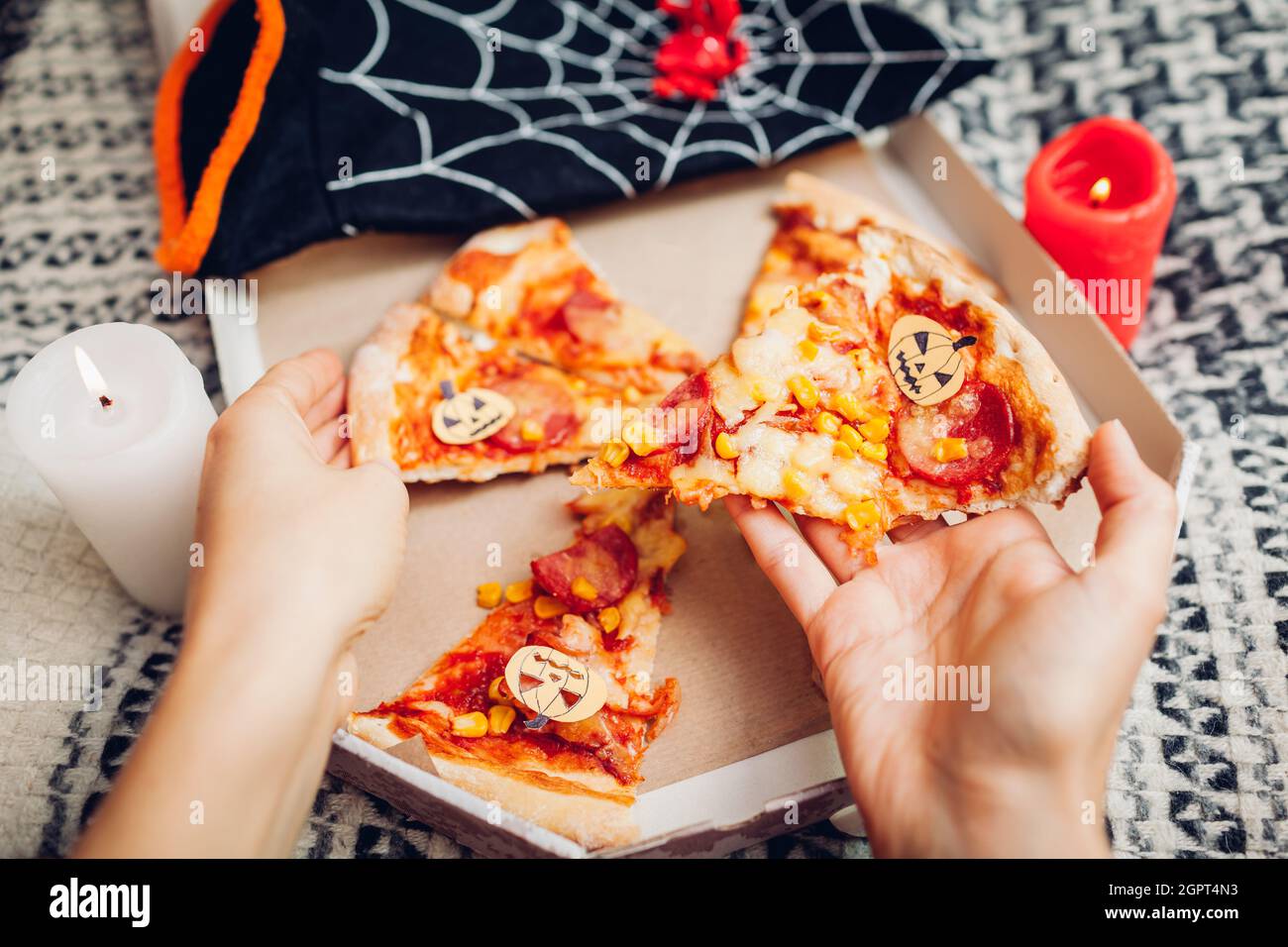 Pizza di Halloween con pumpkins di carta jack-o-lanterna. Festa di festa con candele e costumi. Persone che hanno cibo Foto Stock