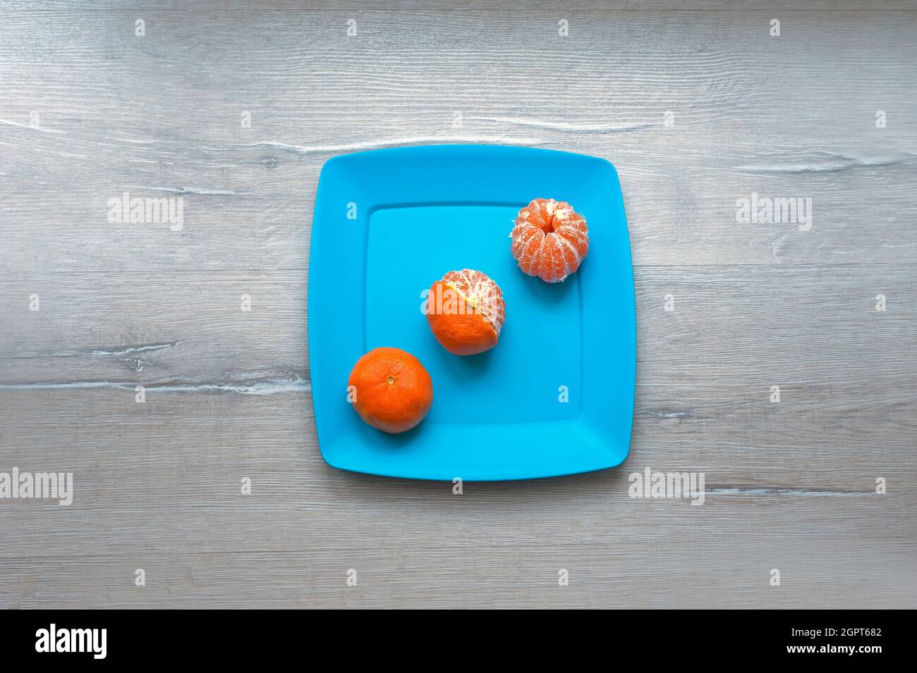 Tre tangerini su una piastra blu Foto Stock
