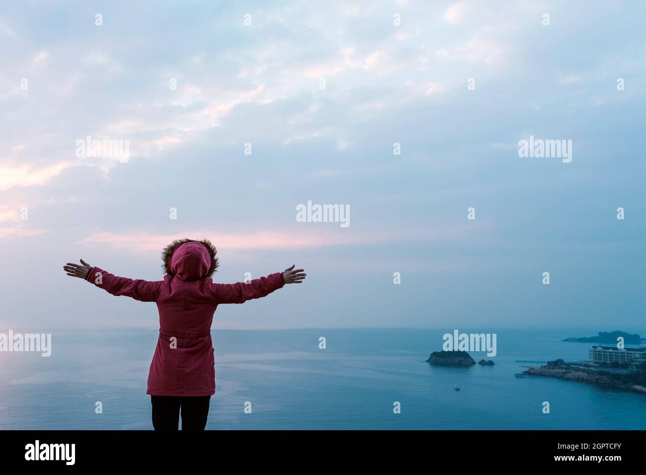 La signora con le braccia tese verso il mare Foto Stock