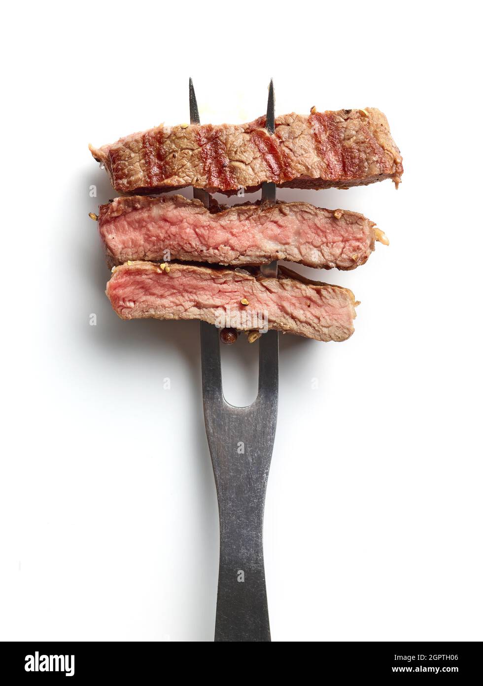 Fettine di bistecca di manzo su forchetta di carne isolate su sfondo bianco; vista dall'alto Foto Stock