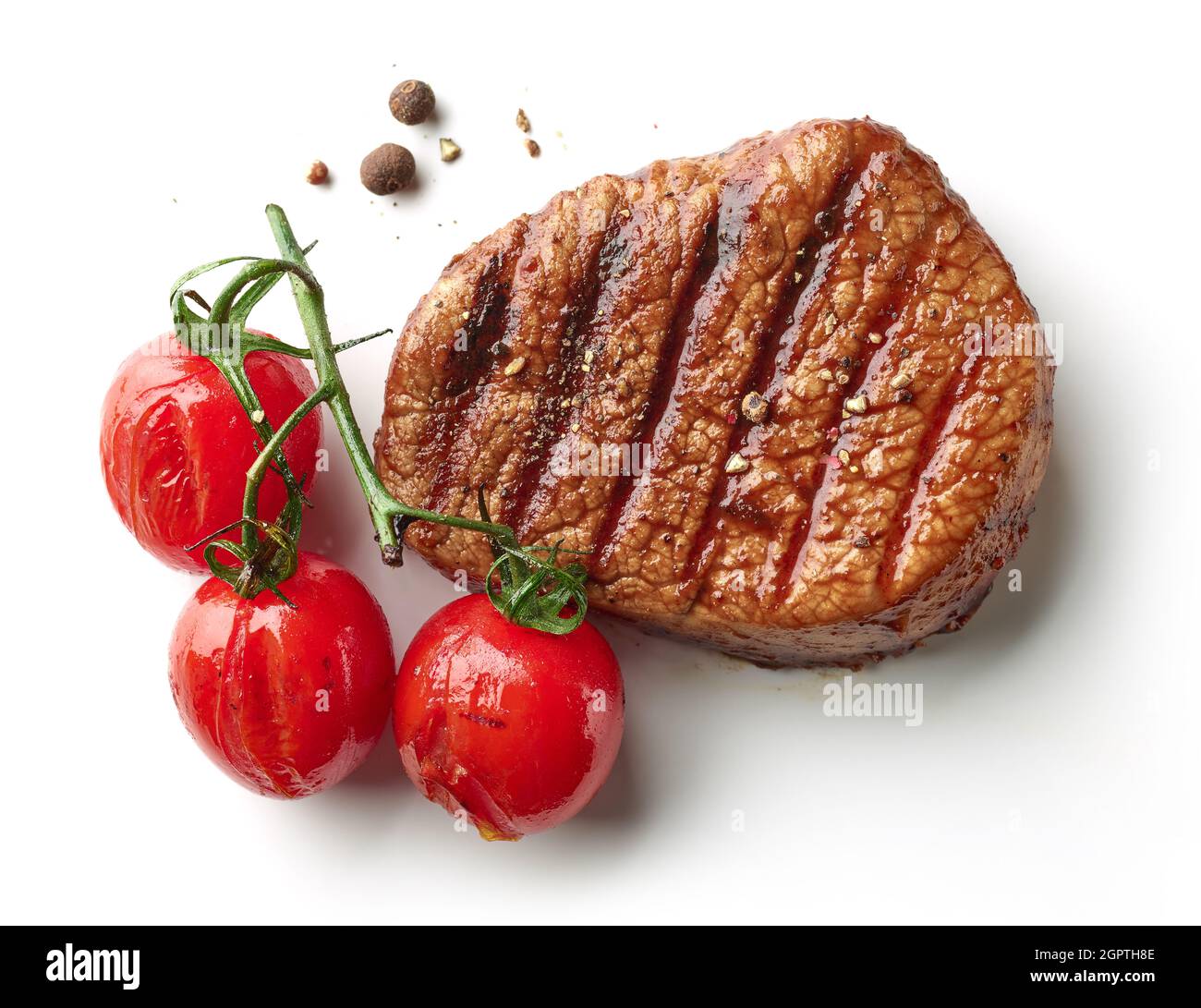 Bistecca di filetto di manzo alla griglia e pomodori isolati su sfondo bianco, vista dall'alto Foto Stock