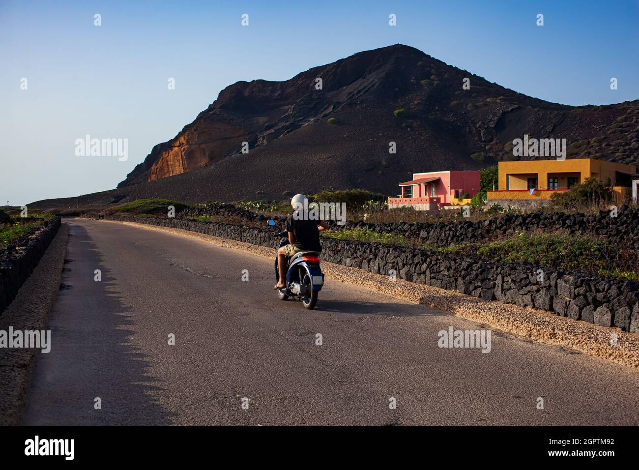 Il giro turistico in scooter, sullo sfondo il Monte Nero famoso vulcano di Linosa, Sicilia. Italia Foto Stock