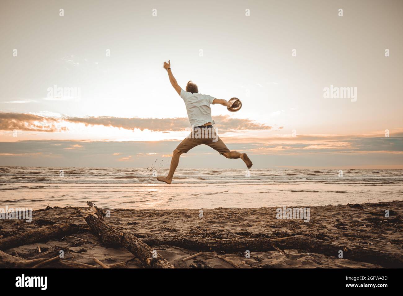 Ragazzo felice godersi le vacanze estive sulla spiaggia al tramonto - giovane uomo che salta sulla spiaggia all'alba - concetto di vacanza Foto Stock