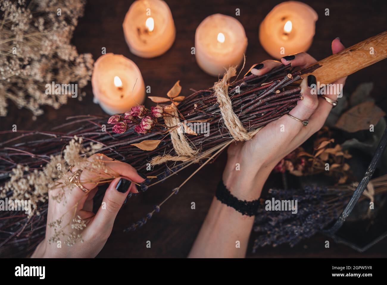 Wiccan Witch che decorano una scopa autoctinata per la celebrazione del Samhain. Scopa fatta a mano su un tavolo di legno scuro Foto Stock