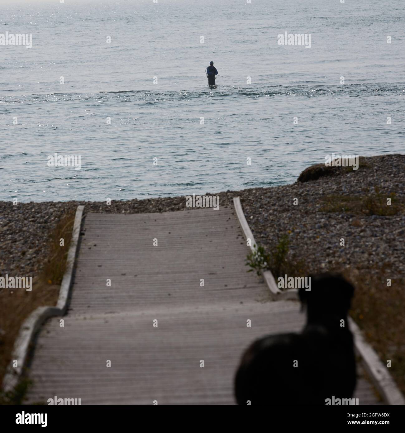 Pescatore visto spiaggia pesca ginocchio in profondità in acqua. Foto Stock
