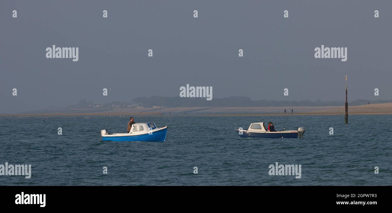 La gente si prepara a pescare in mare in due piccole barche sulla costa meridionale del Regno Unito in estate. Foto Stock