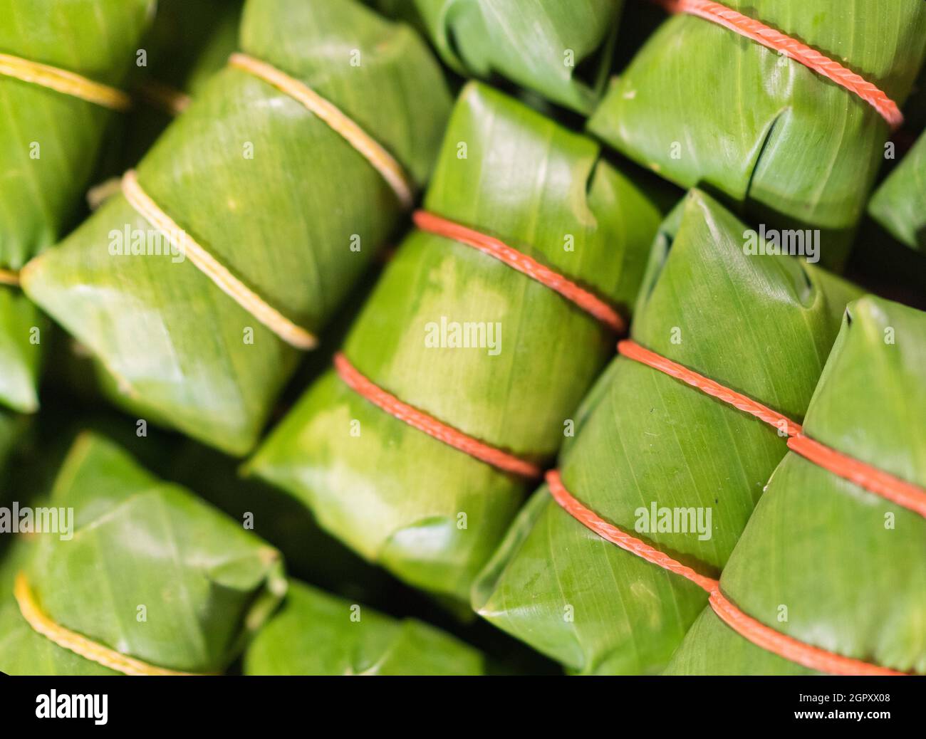 Khao tom - popolare dessert laotiano e thailandese. Riso Sticky al vapore con ripieno avvolto in foglie di banana. Immagine di concetto della cucina asiatica. Foto Stock