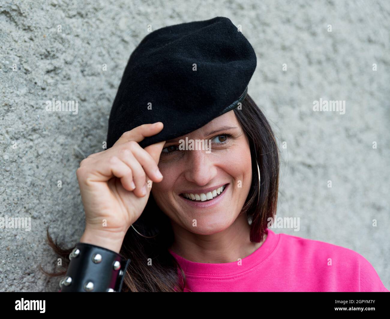 Primo piano Ritratto di ragazza sorridente che indossa un berretto nero e  un abito Fuchsia e un braccialetto con borchie Foto stock - Alamy