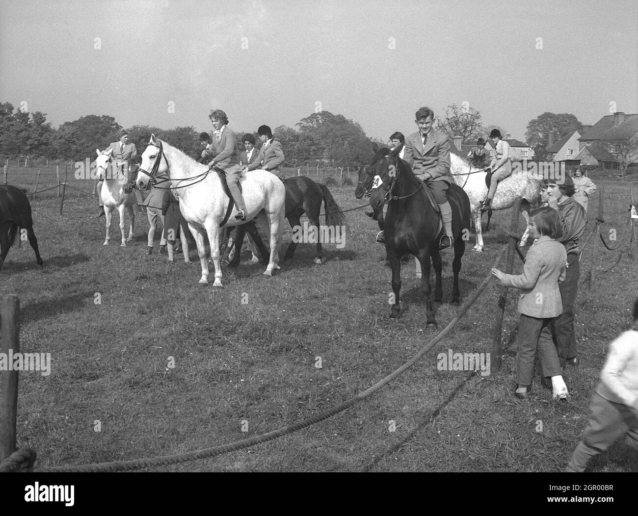 Anni '50, storici, ragazzi e girl cavalieri sui loro cavalli, alcuni indossando caschi, alcuni no, fuori nel ring di raccolta, una speciale rampata fuori warm-up area in una competizione di eventi, West Sussex, Inghilterra, Regno Unito. Per alcuni piloti, l'anello di raccolta può essere nervosa-racking, più così che l'arena di competizione. Foto Stock