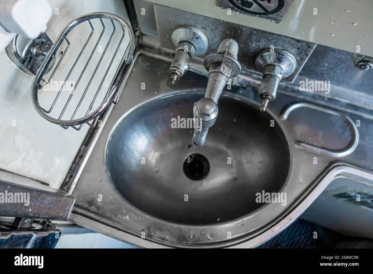 Il lavandino in metallo nel bagno del treno Couchette auto carrozza nella classe economica della famiglia 61 che trasportano passeggeri in paesi ex URSS Foto Stock