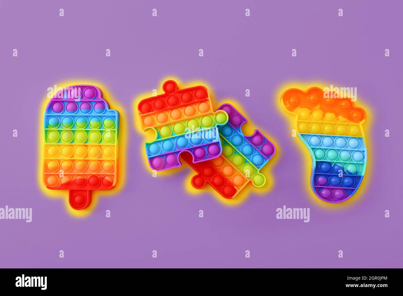 Pop IT colorato Bubble sensoriale Fidget Giocattoli di diverse forme su sfondo viola, vista dall'alto Foto Stock