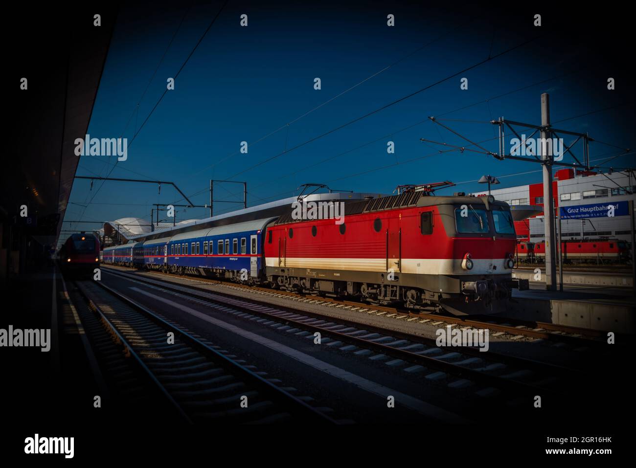 Treno passeggeri elettrico rosso alla stazione di Graz in estate soleggiata fresca mattina Foto Stock
