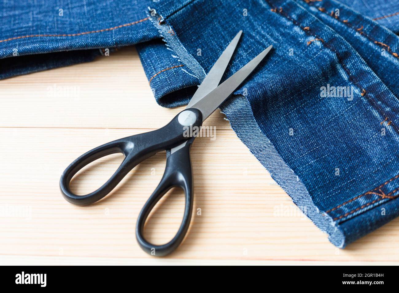 Tagliare pezzi di pantaloni lunghi in denim su un fondo di legno Foto stock  - Alamy