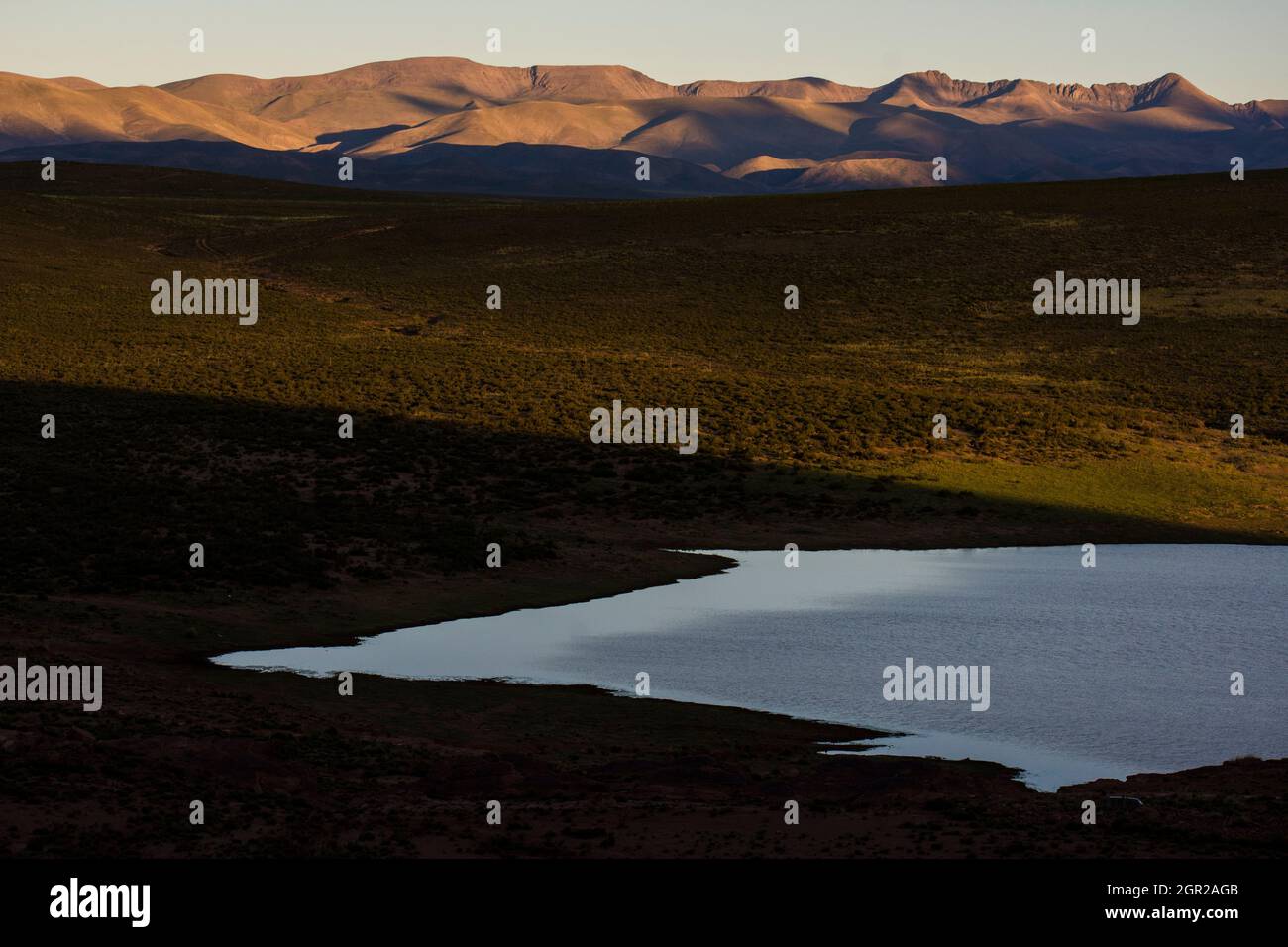 Riva del lago nel tardo pomeriggio con il sole sulle montagne di sfondo a Jujuy, Argentina Foto Stock