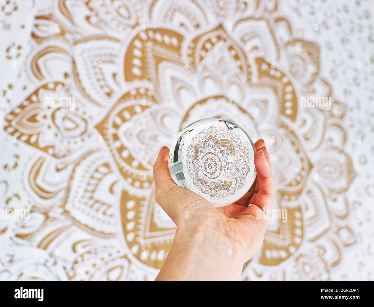 Sfera di cristallo Mandala Oro bianco con mano Foto Stock