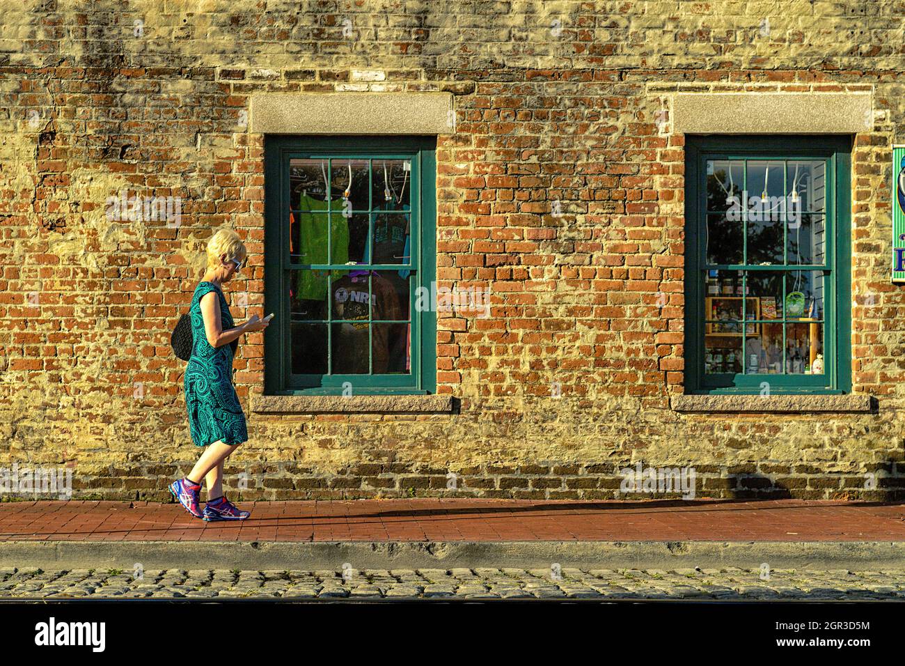 Le donne che camminano oltre i vecchi magazzini di mattoni rossi restaurati della zona pedonale di Factors in Savannah Georgia Foto Stock