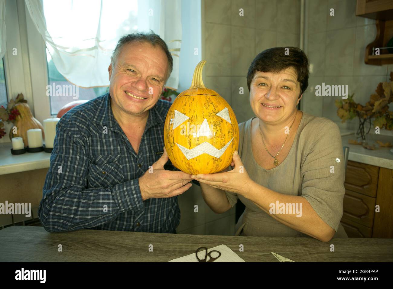 Facendo Jack o'Lantern a casa. La zucca è pronta per affettare. L'uomo e la donna sono felici del loro lavoro e ridono e scherzano .. Foto Stock