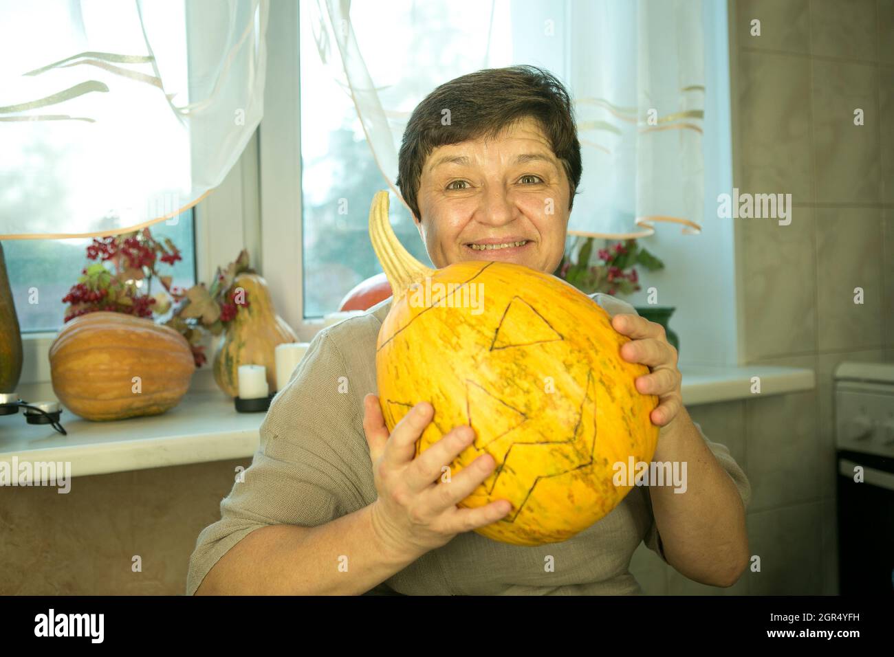 Halloween. Facendo Jack o'Lantern a casa. Processo di creazione del modello di thread Jack o'Lantern. Una donna prepara la zucca per l'intaglio. Foto Stock