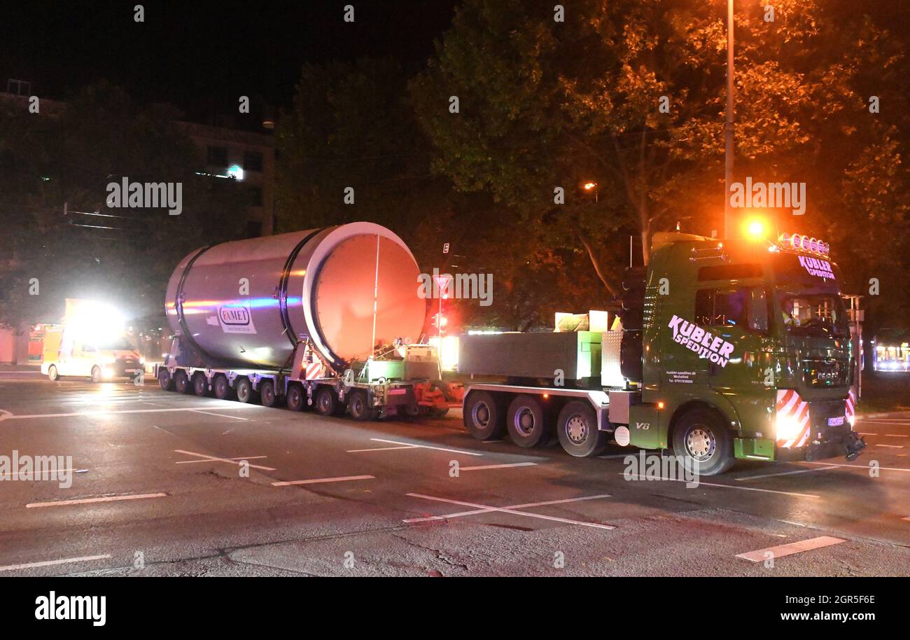 Monaco di Baviera, Germania. 30 settembre 2021. Un veicolo pesante trasporta un silo di grandi dimensioni allo stabilimento di CHP del Sud di Monaco. Durante il tragitto, il team si spegne a Sonnenstraße verso Schwanthalerstraße, mentre le linee aeree del tram vengono sollevate con una piattaforma di sollevamento. Il trasporto è iniziato durante la notte attraverso il percorso Ingolstädter Straße verso Leopoldstraße attraverso il centro della città, via Sonnenstraße verso Theresienhöhe, Brudermühlstraße verso la centrale combinata di calore e potenza di Schäftlarnstraße. Credit: Felix Hörhager/dpa/Alamy Live News Foto Stock