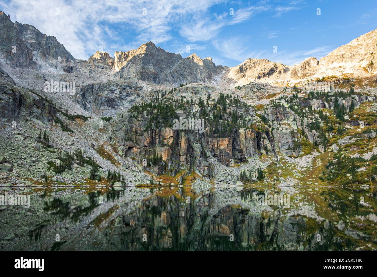 Mattina tranquilla in un lago alpino durante l'alba con cime aspre e un riflesso nelle Montagne Rocciose, Colorado, Stati Uniti Foto Stock