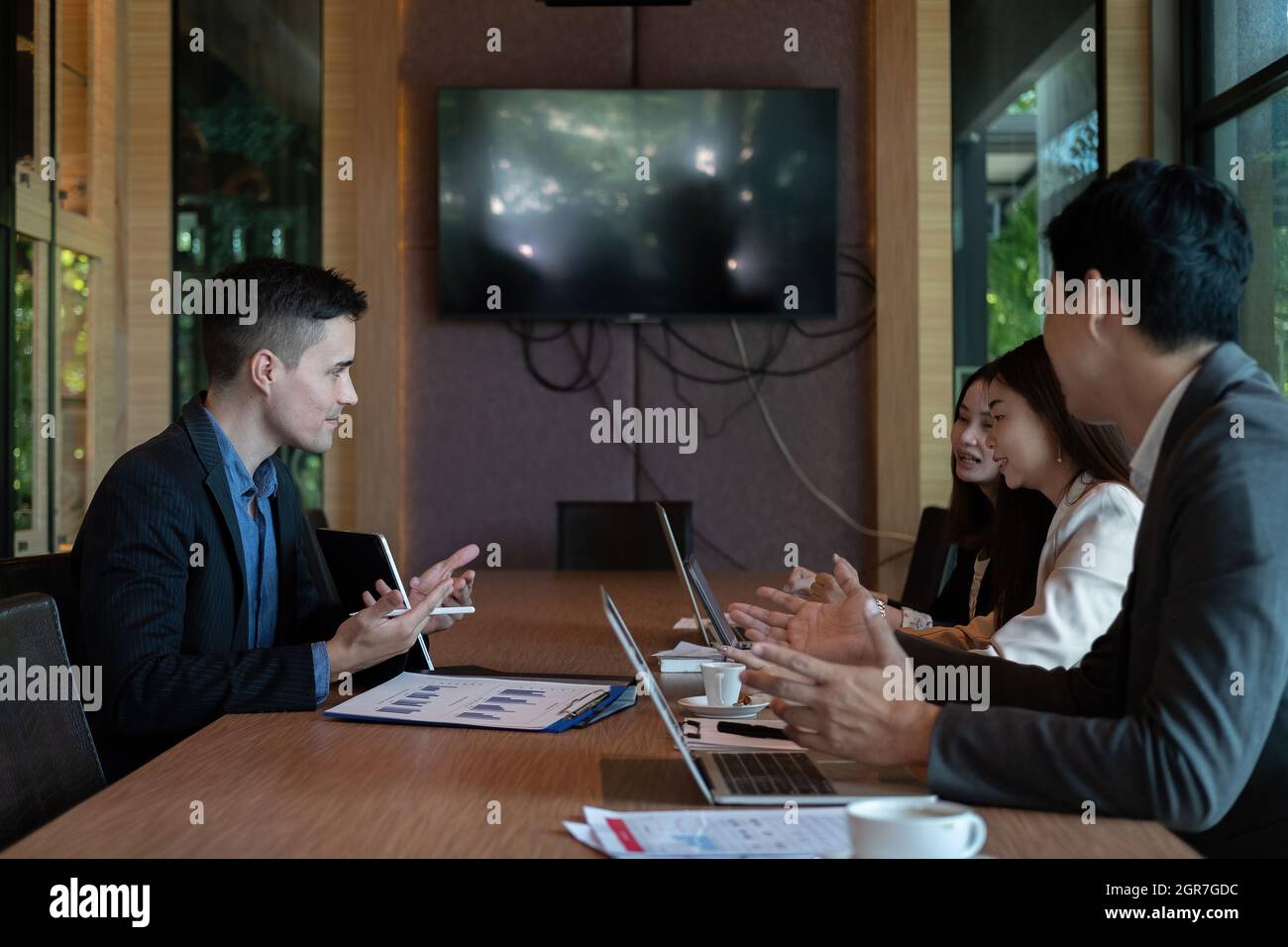 Un gruppo di uomini d'affari si riunisce per analizzare i dati per il piano di marketing nella sala riunioni Foto Stock