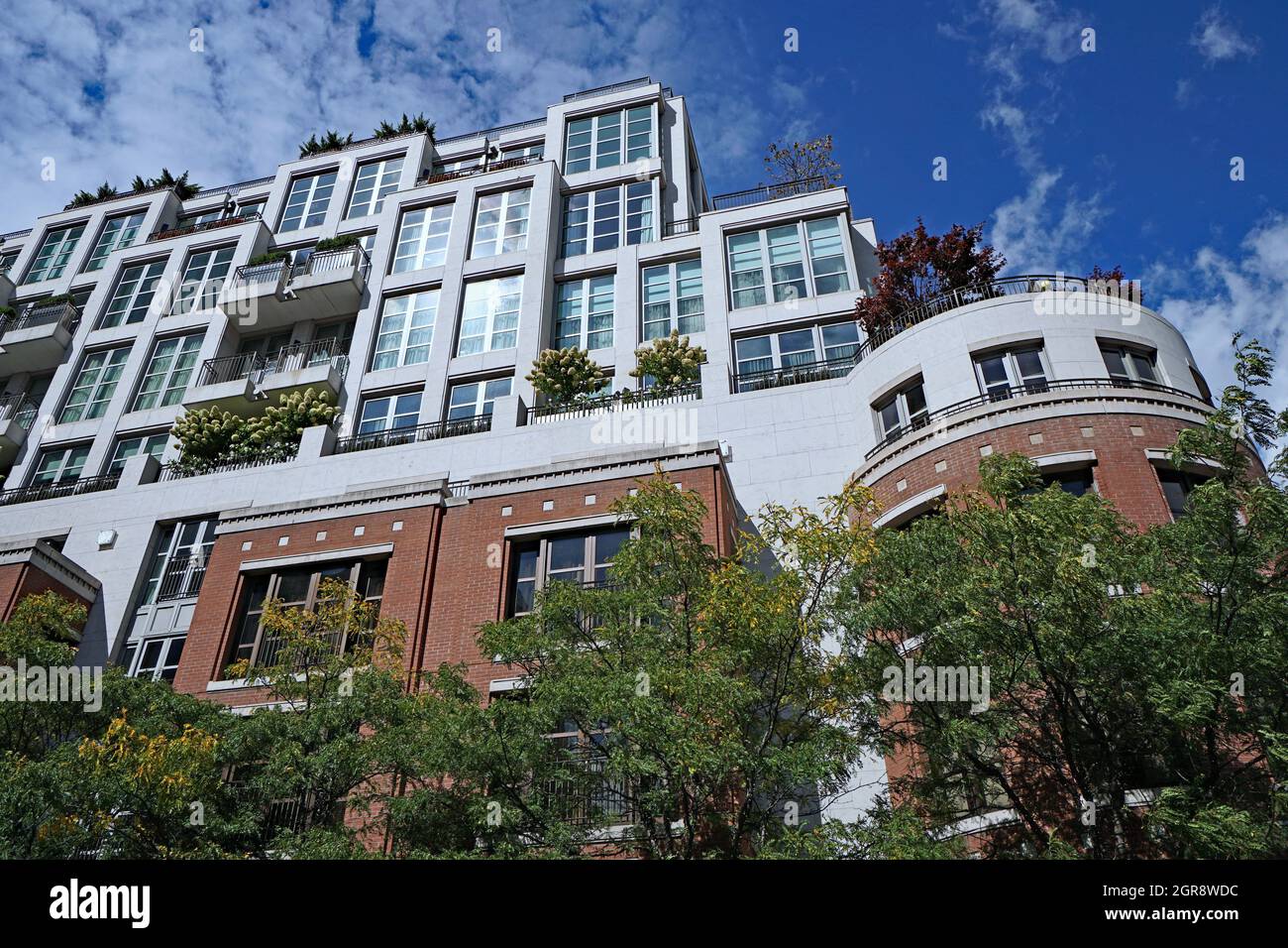 edificio circondato da alberi, con piante su balconi e tetto, che è buono per l'ambiente Foto Stock